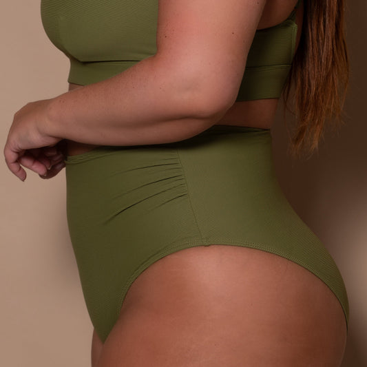 plussize woman wearing a khaki green high waist bikini against a beige background