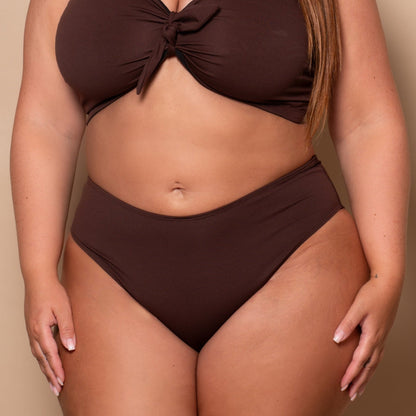 plussize woman wearing a chocolate brown bikini set against a beige background