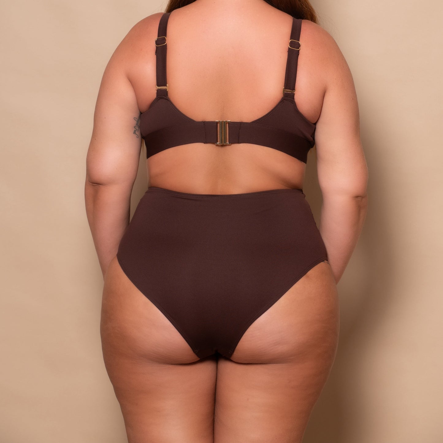 plussize woman wearing a chocolate brown bikini set against a beige background