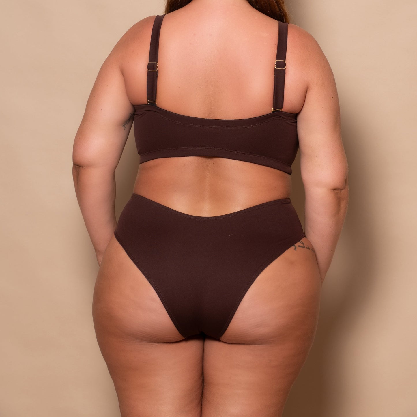 plussize woman wearing a chocolate brown bikini set against a beige background