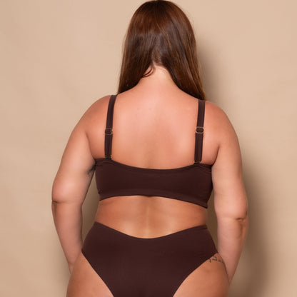 plussize woman wearing a chocolate brown bikini set against a beige background