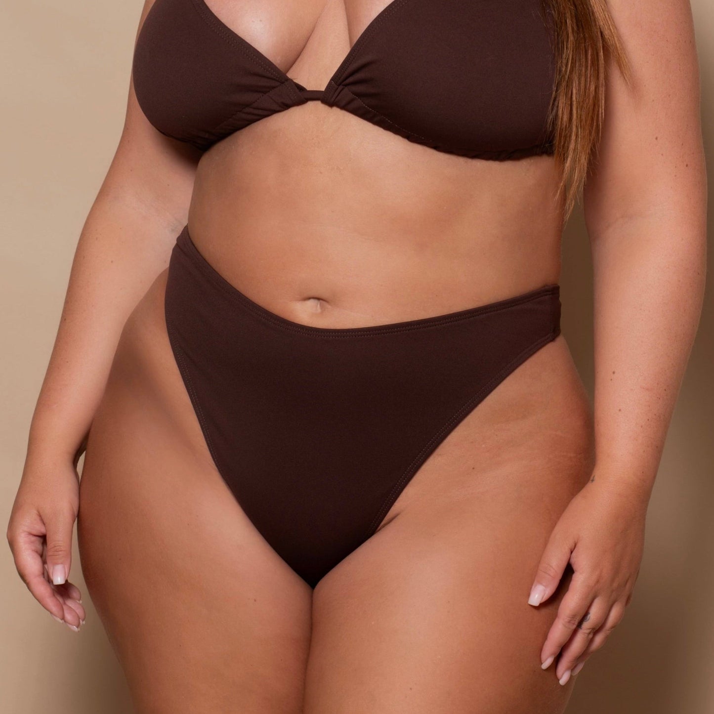 plussize woman wearing a chocolate brown bikini set against a beige background