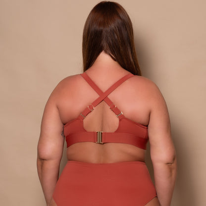 plussize woman wearing a rust red bikini set against a beige background