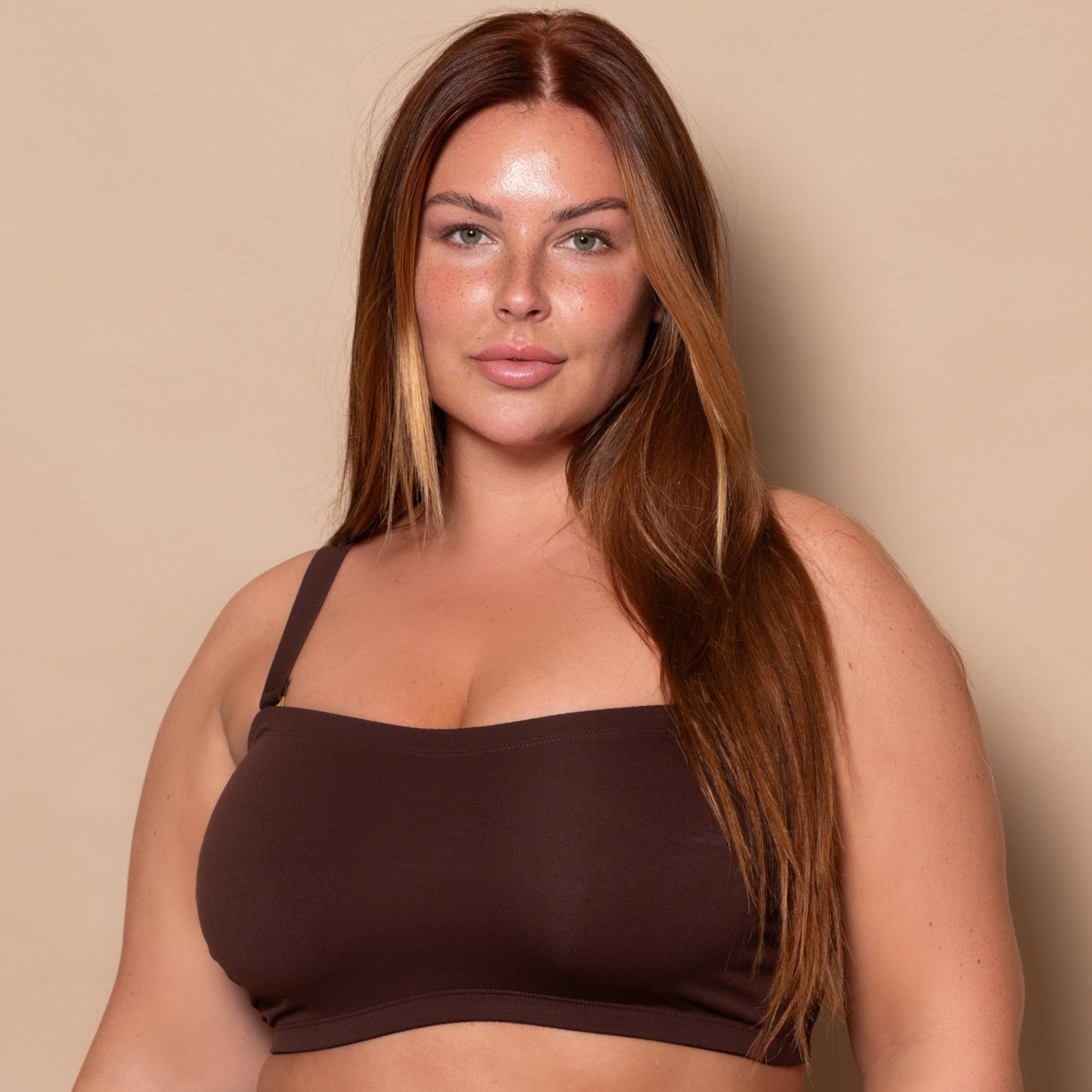 plussize woman wearing a chocolate brown bikini set against a beige background
