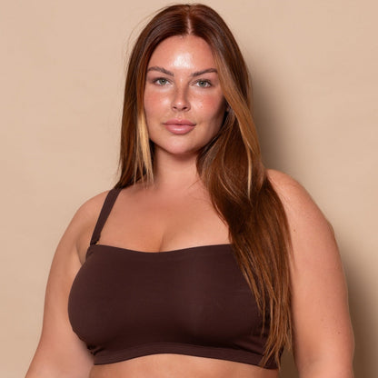 plussize woman wearing a chocolate brown bikini set against a beige background