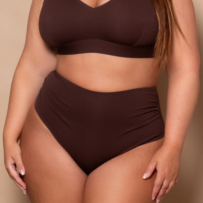 plussize woman wearing a chocolate brown bikini set against a beige background