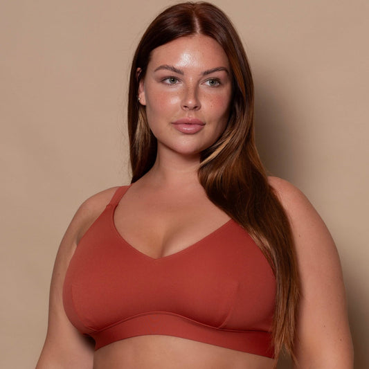 plussize woman wearing a rust red bikini set against a beige background