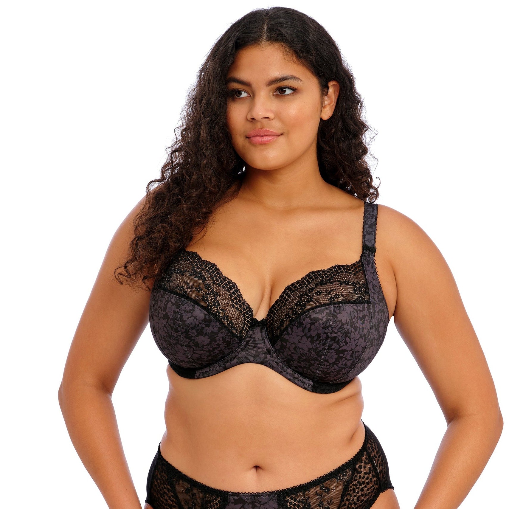 Curvy Woman wearing a black lace lingerie set on a white background