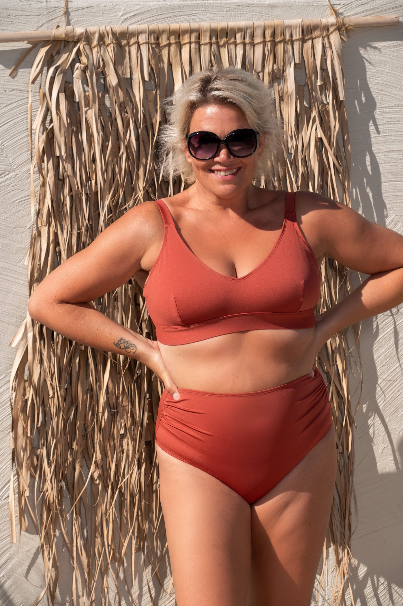 Woman in a rust-red bikini standing against a textured wall