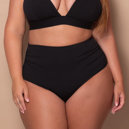 curvy woman wearing a black bikini against a beige background