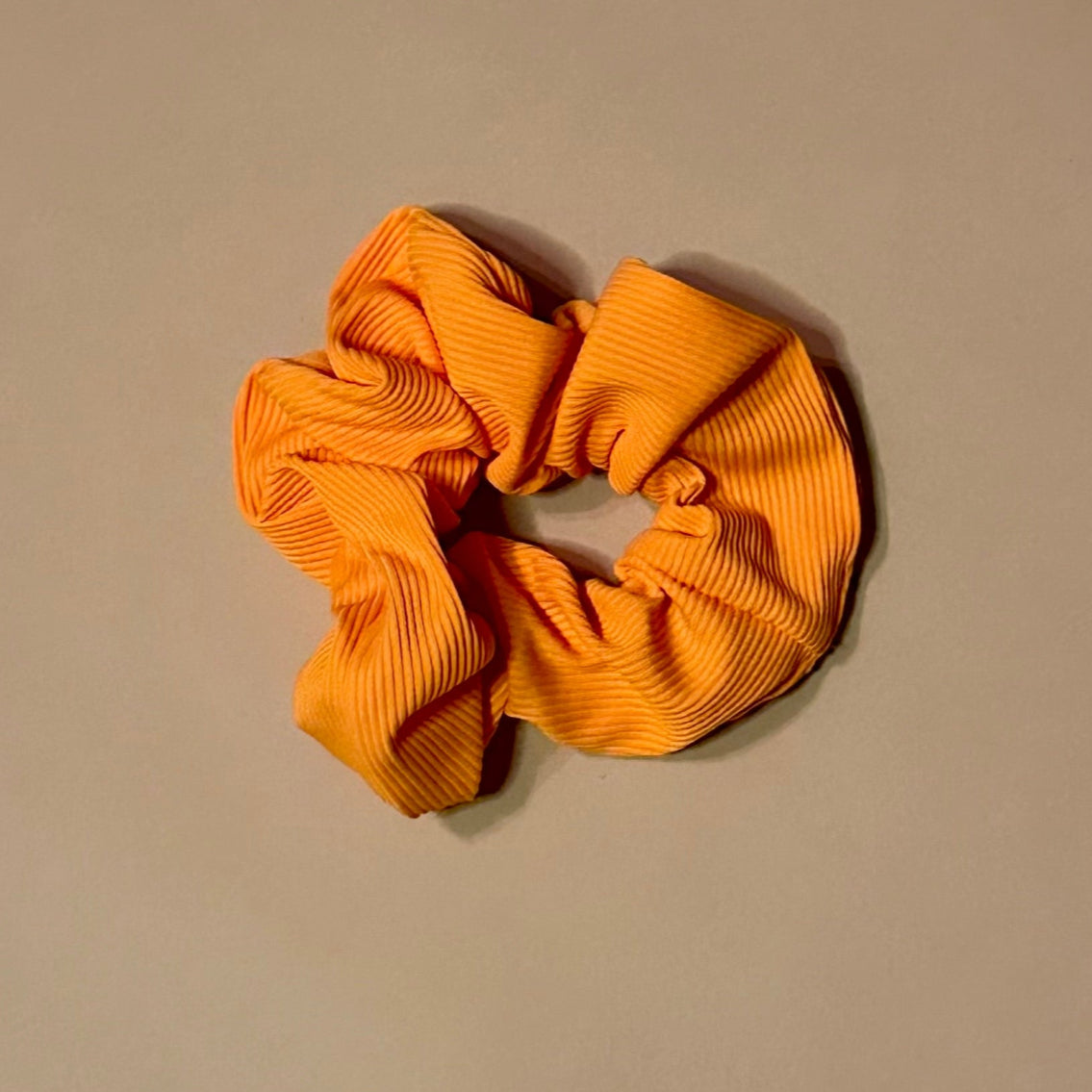 yellow ribbed scrunchie on a beige background