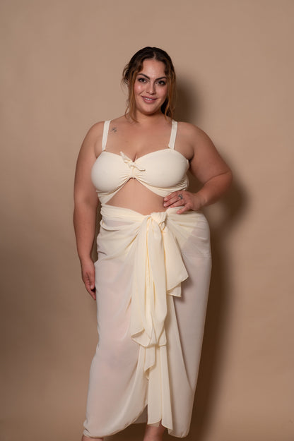 plussize woman wearing a white cream bikini with pareo cover up against a beige background