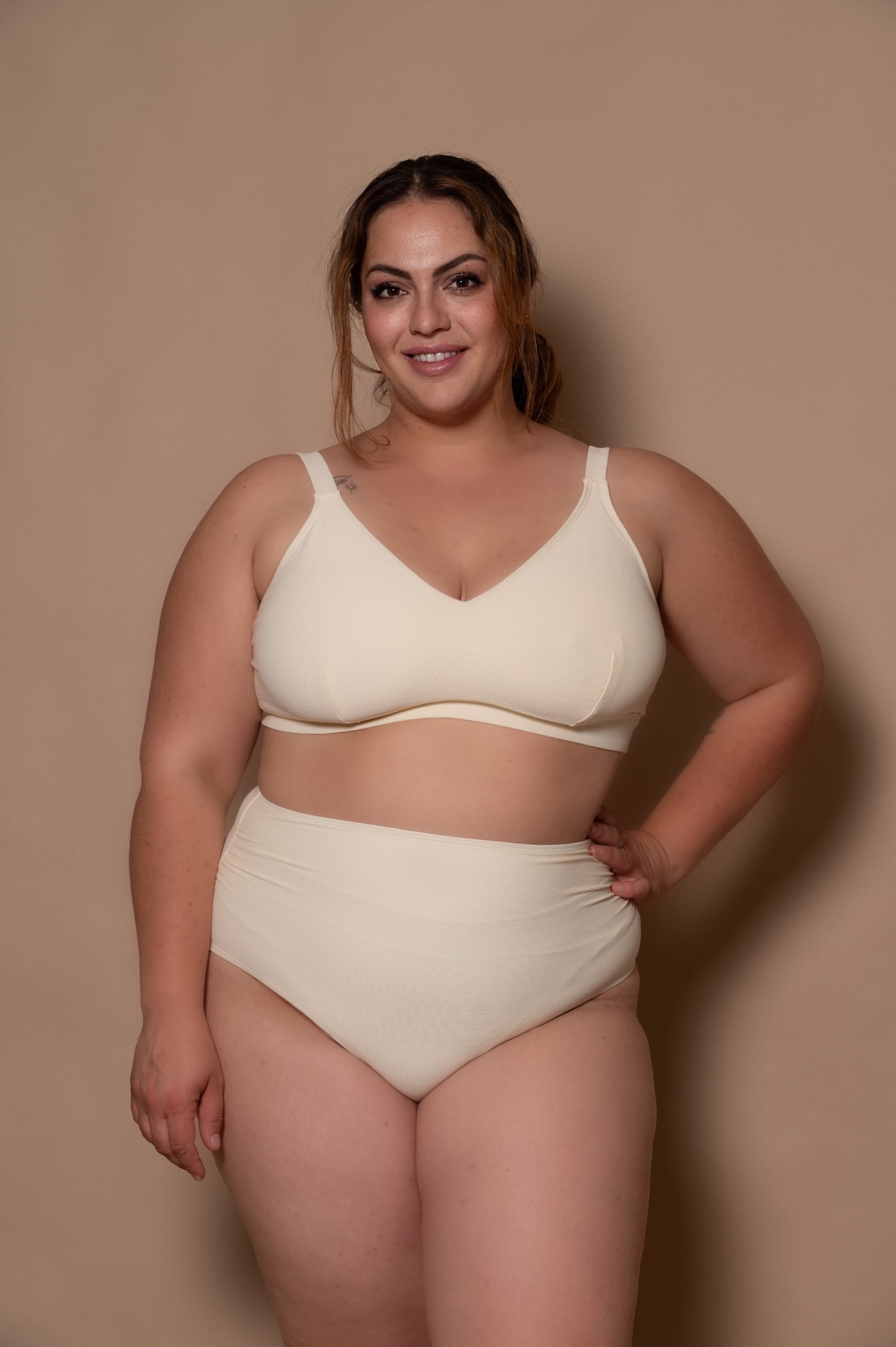 plussize woman wearing a white cream bikini  against a beige background