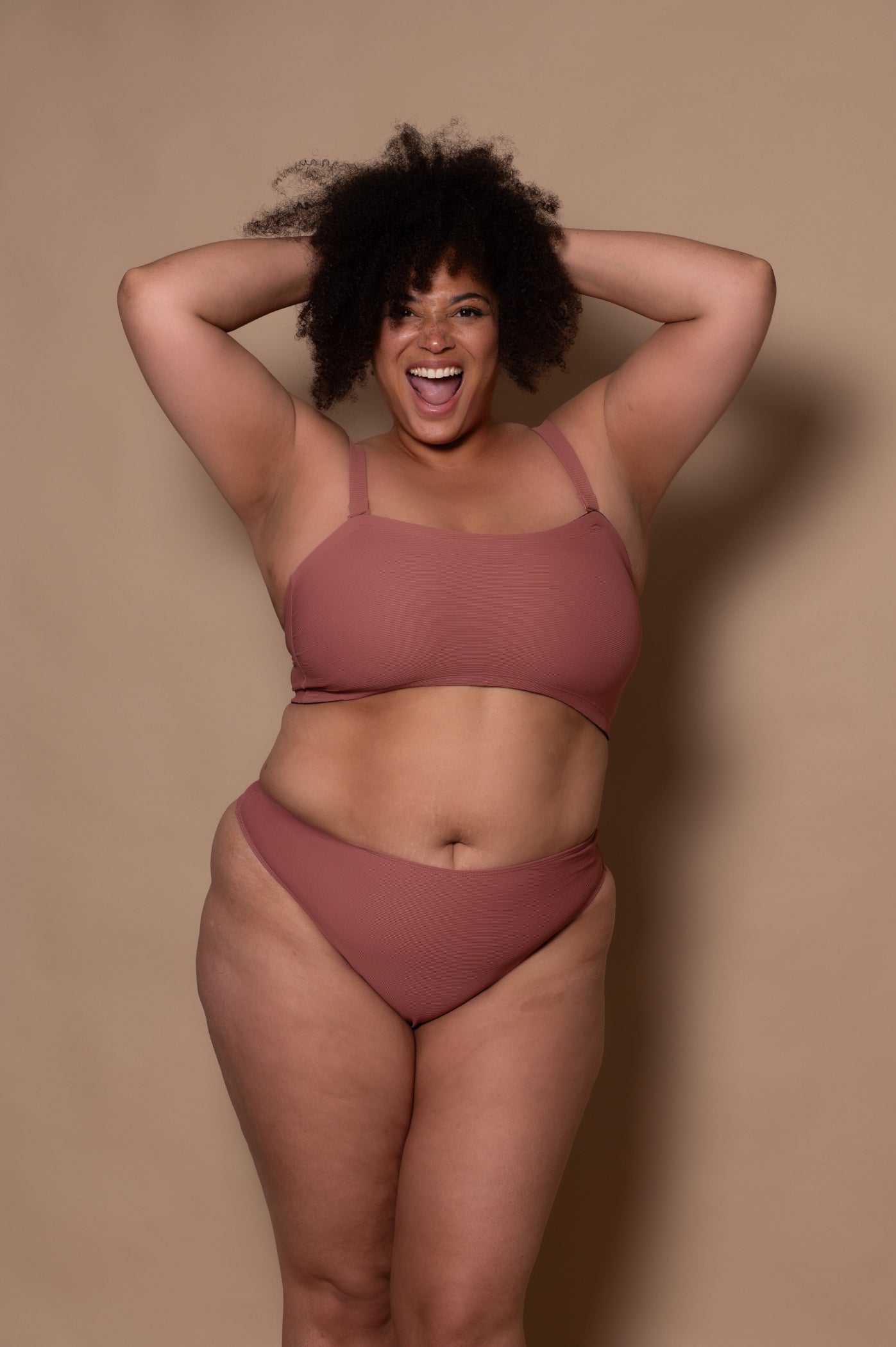 plussize woman wearing a rosewood bikini against a beige background