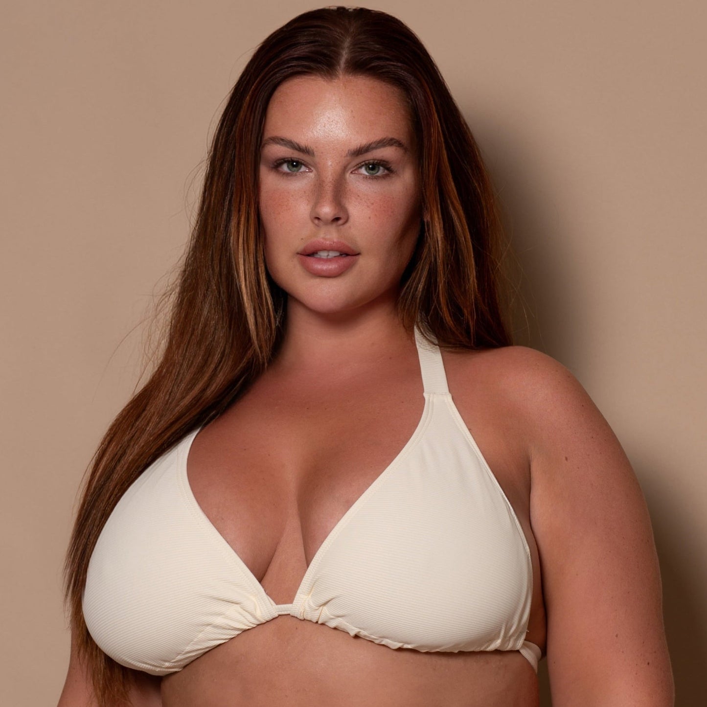 plussize woman wearing a cream white bikini  against a beige background
