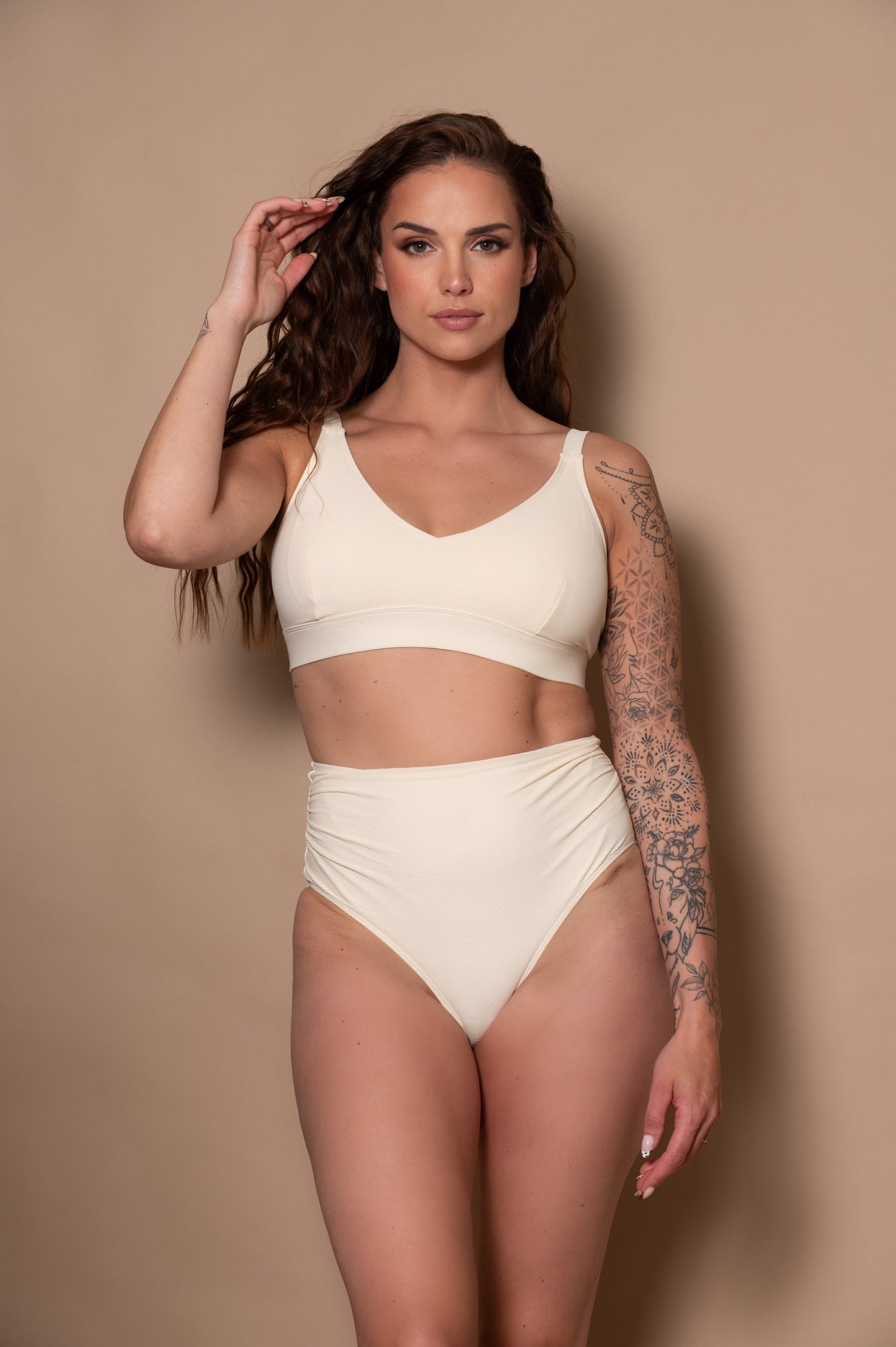 woman wearing a white cream bikini  against a beige background