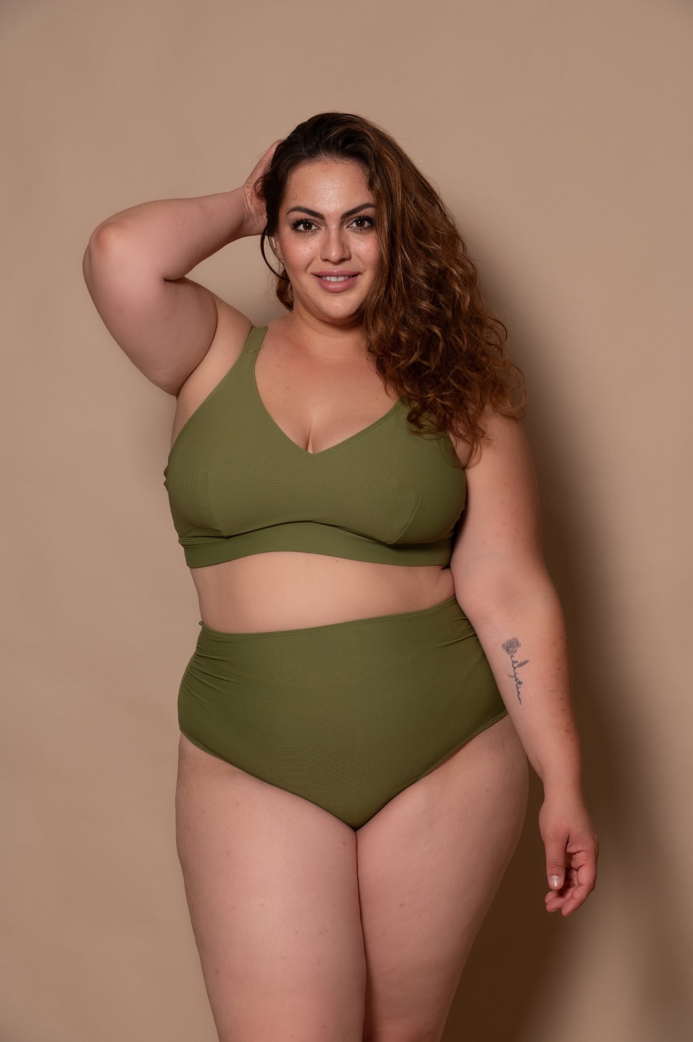 plussize woman wearing a khaki green bikini  against a beige background