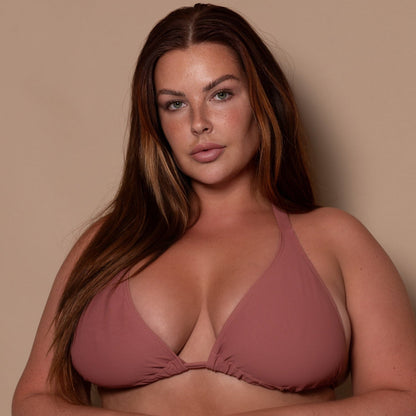 plussize woman wearing a rosewood pink triangle bikini  against a beige background