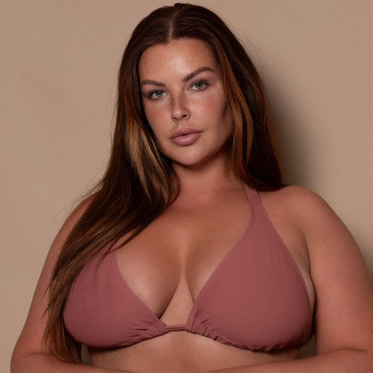 plussize woman wearing a rosewood pink triangle bikini  against a beige background