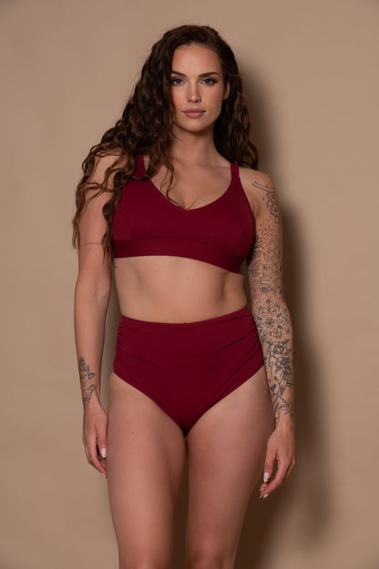 woman wearing a pomegranate wine red bikini against a beige background