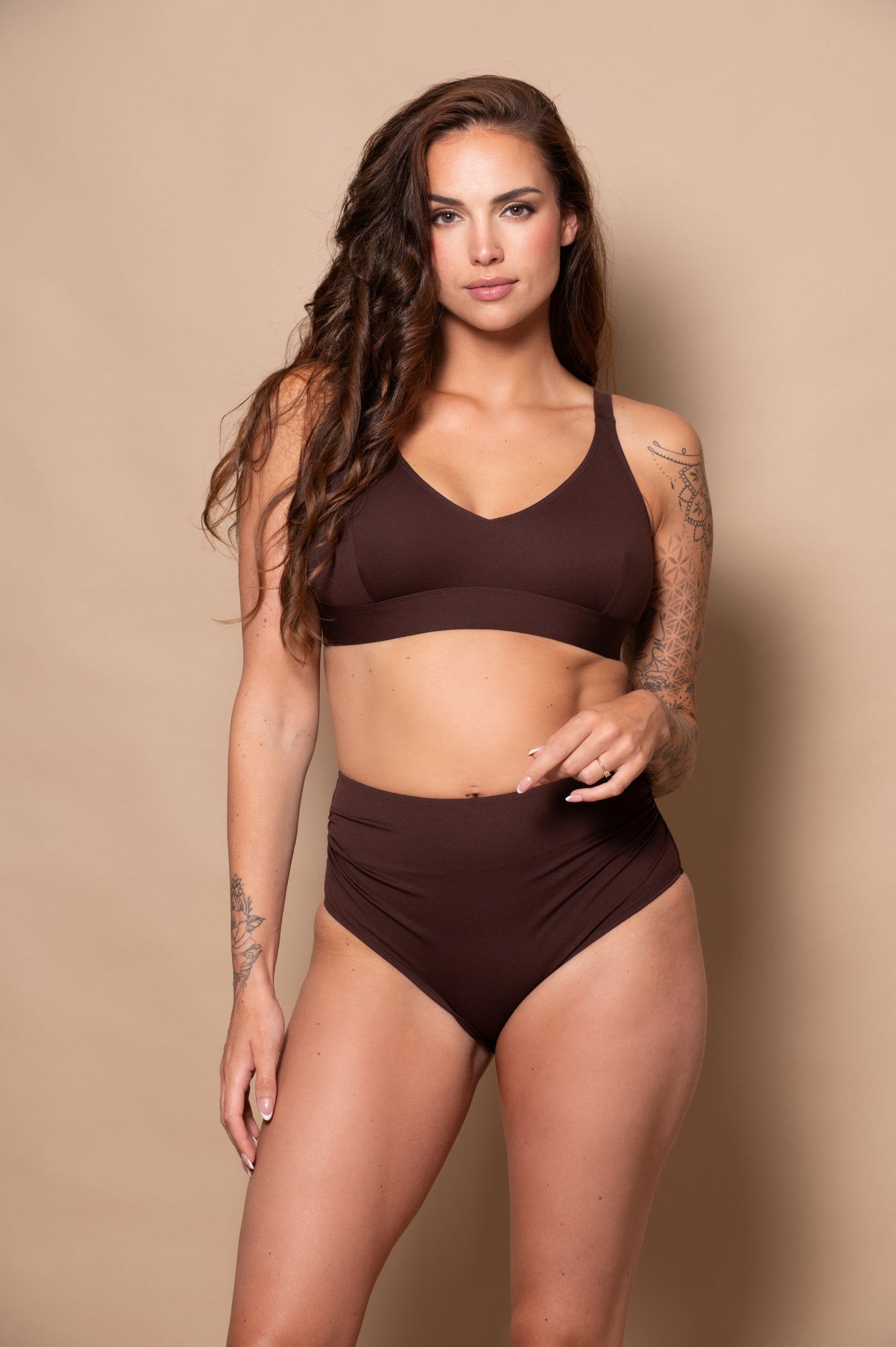 woman wearing a chocolate brown bikini  against a beige background