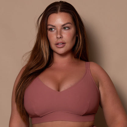 plussize woman wearing a rosewood pink bikini  against a beige background
