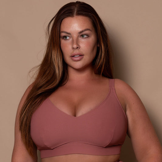 plussize woman wearing a rosewood pink bikini  against a beige background