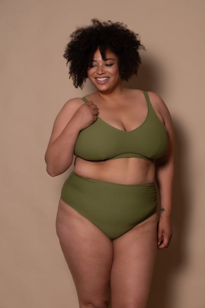 plussize woman wearing a khaki green bikini  against a beige background