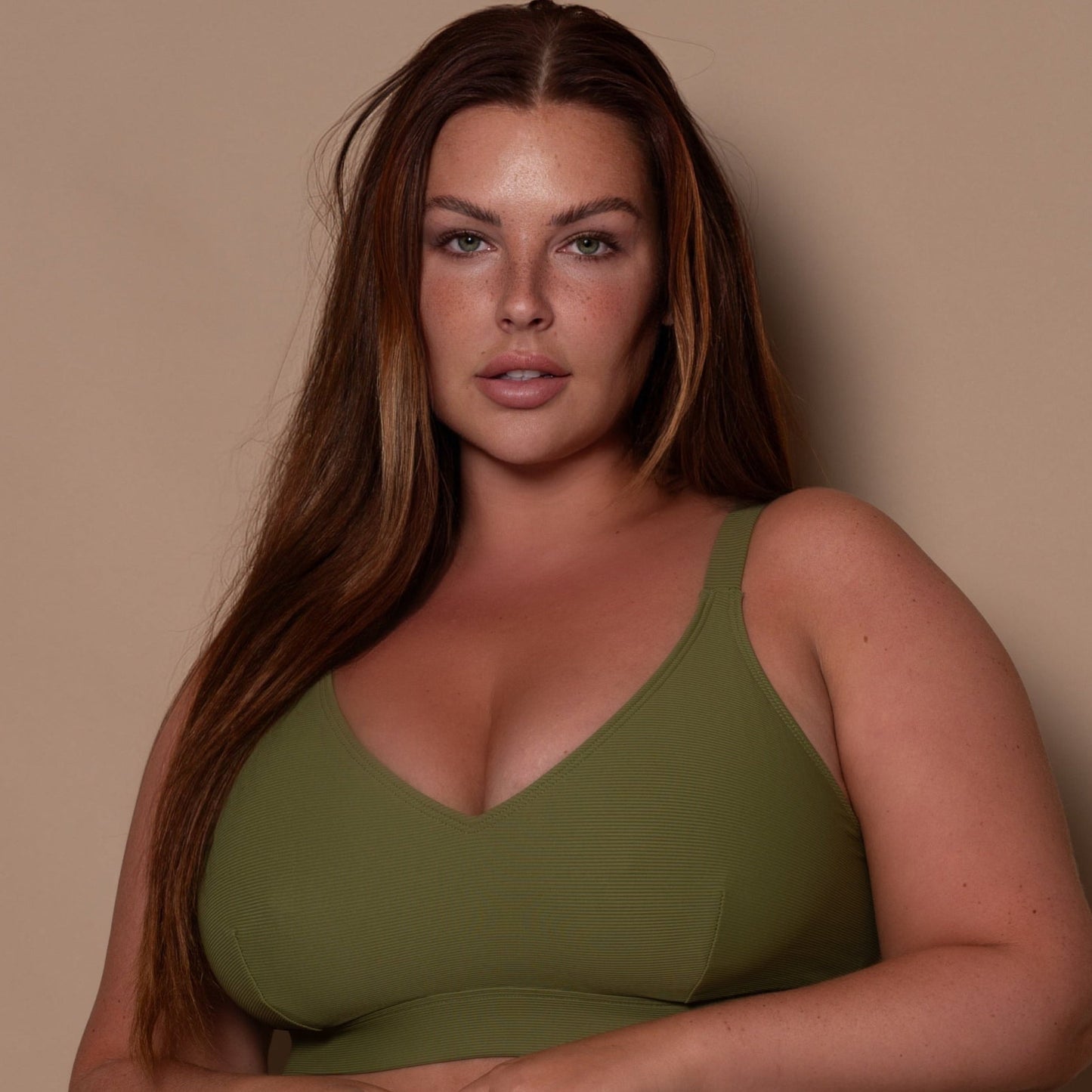plussize woman wearing a khaki green bikini  against a beige background