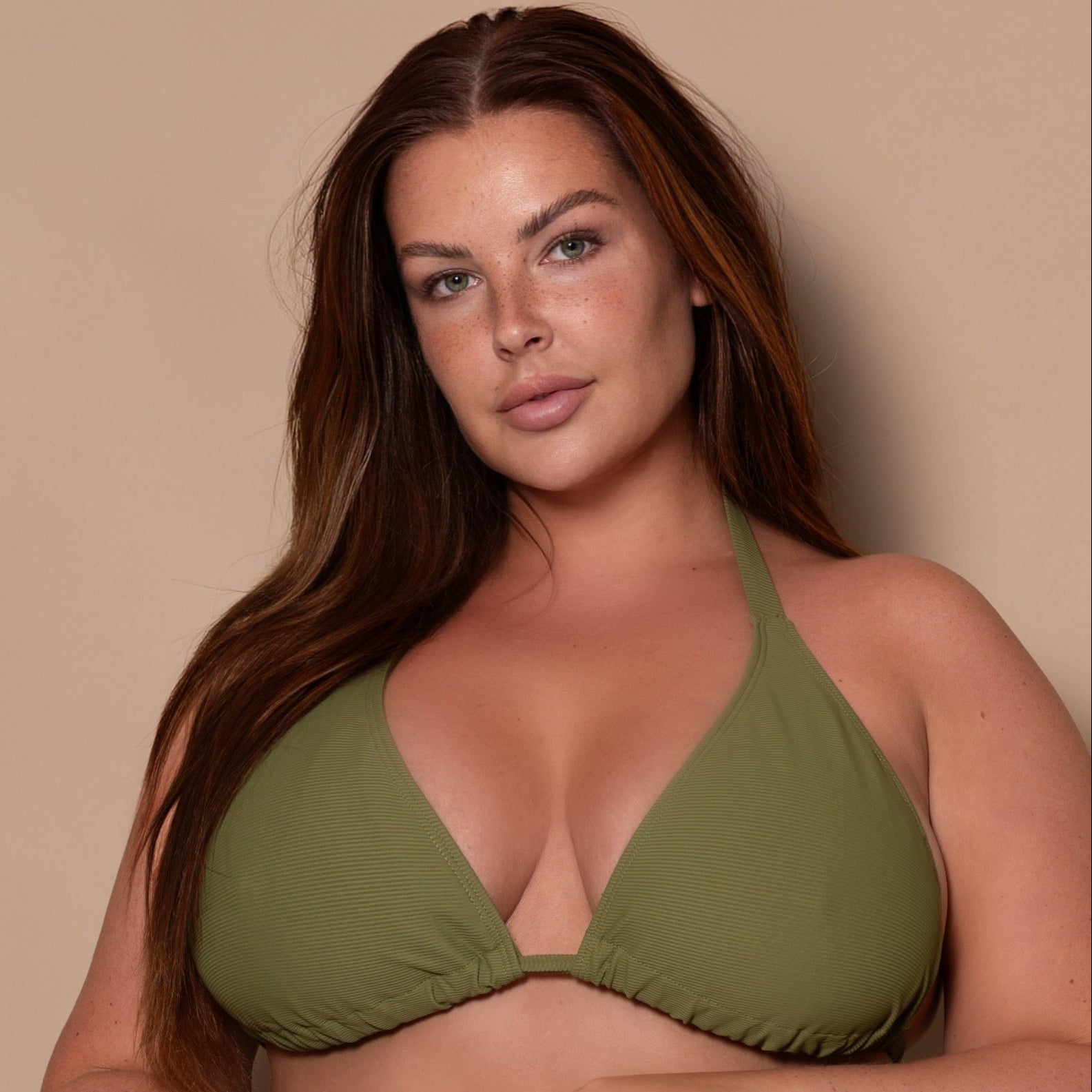 plussize woman wearing a khaki green triangle bikini  against a beige background