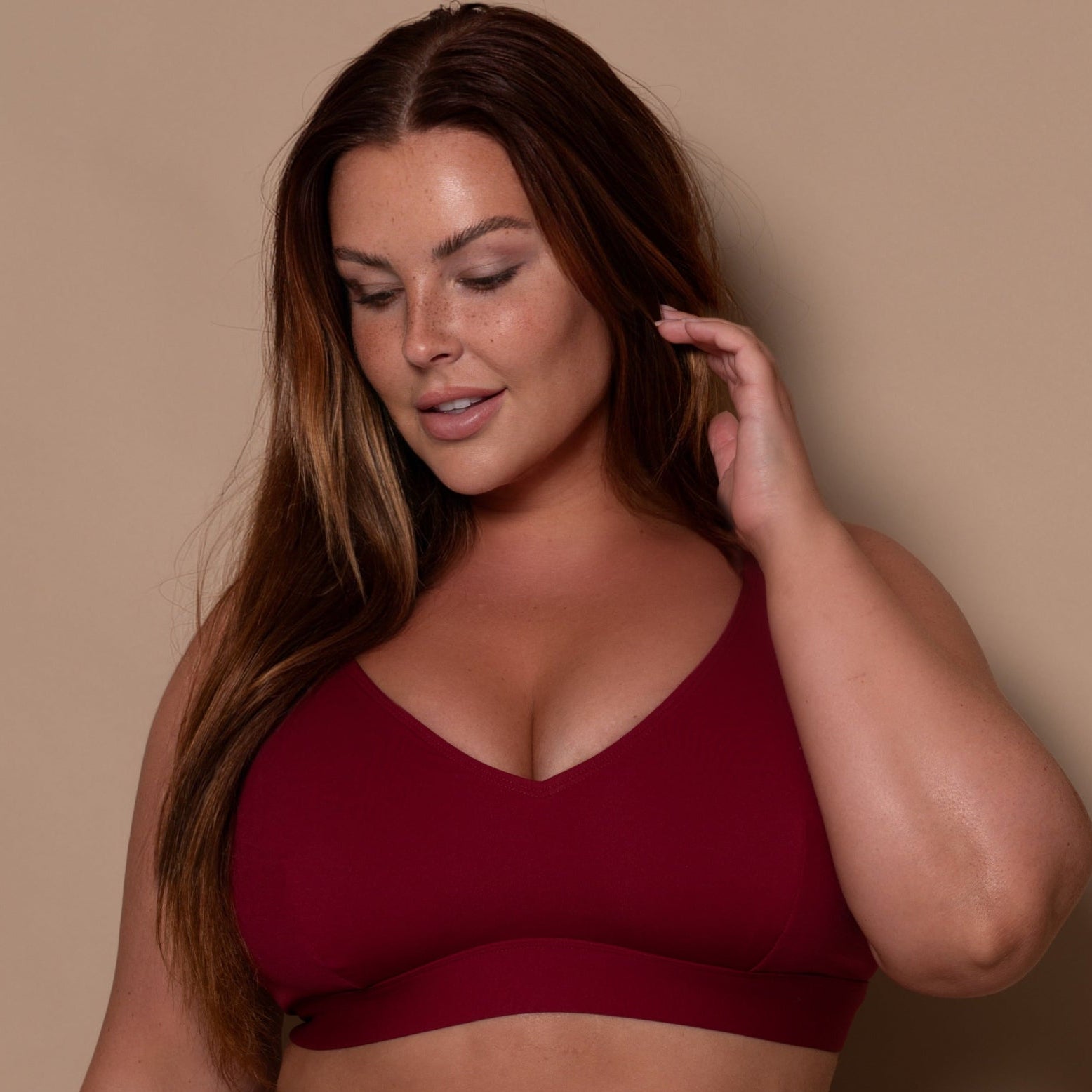plussize woman wearing a pomegranate red bikini  against a beige background