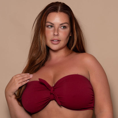 plussize woman wearing a pomegranate red bikini  against a beige background