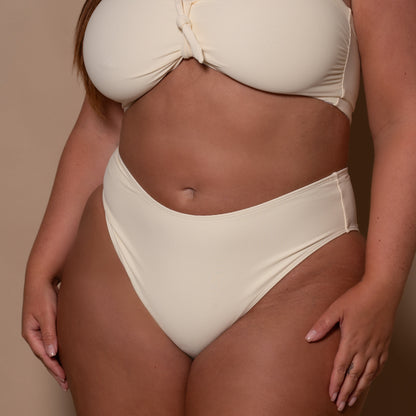 plussize woman wearing a cream white bikini  against a beige background
