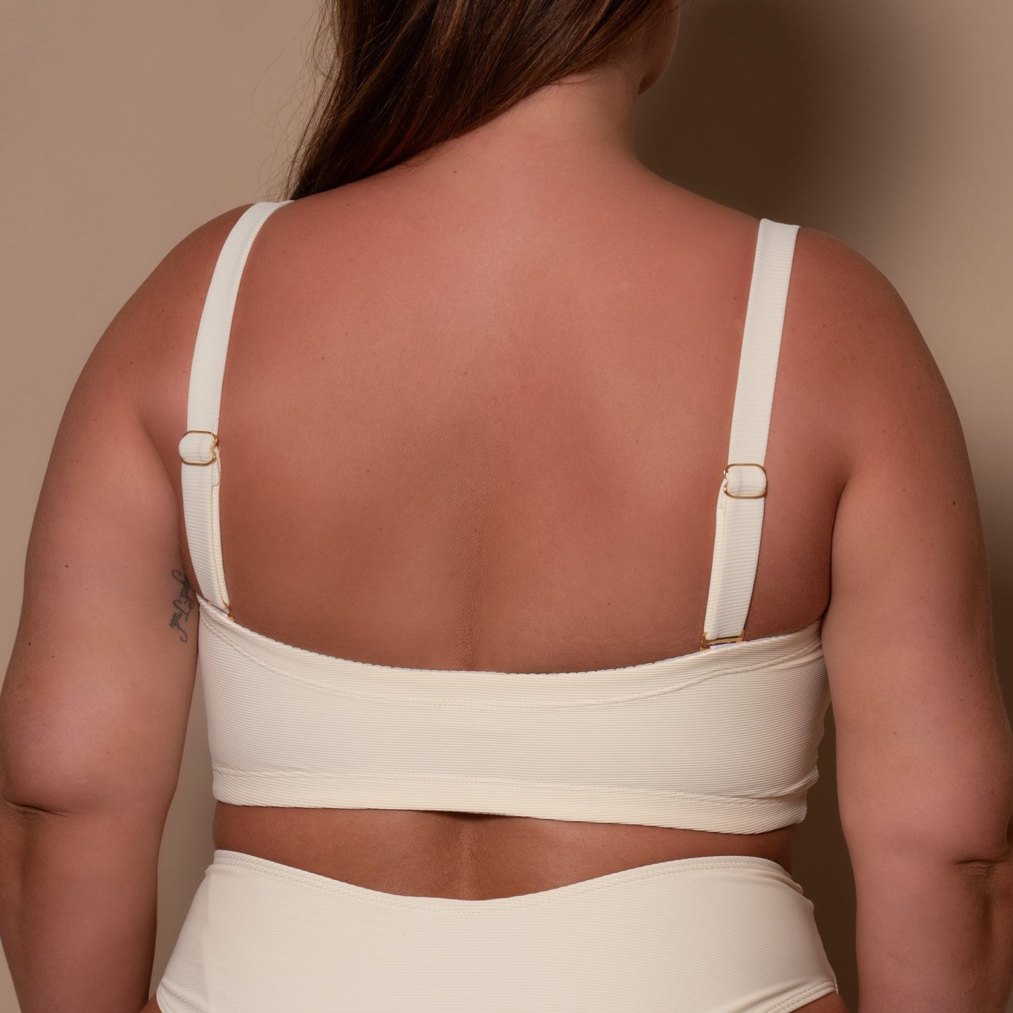 plussize woman wearing a cream white bikini  against a beige background
