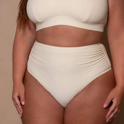 plussize woman wearing a cream white high waist bikini  against a beige background