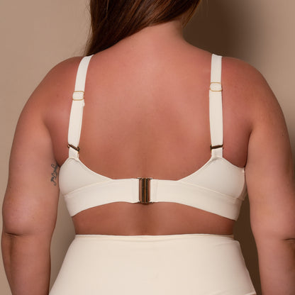 plussize woman wearing a cream white bikini  against a beige background
