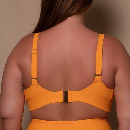 curvy woman wearing a yellow ribbed bikini against a beige background