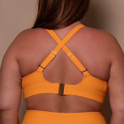 curvy woman wearing a yellow ribbed bikini against a beige background