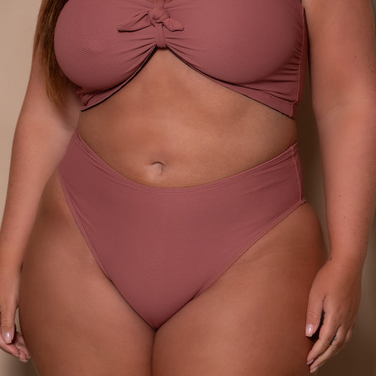 plussize woman wearing a rosewood pink briefs bikini  against a beige background