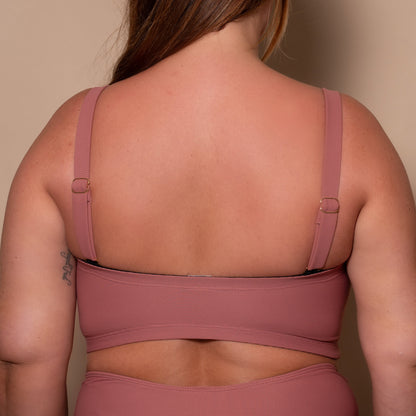 plussize woman wearing a rosewood pink bandeau bikini  against a beige background