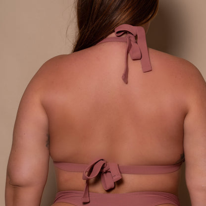 plussize woman wearing a rosewood pink triangle bikini  against a beige background