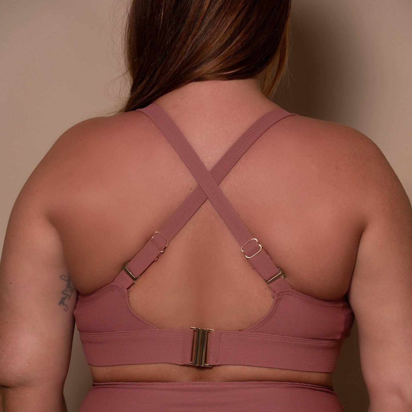 plussize woman wearing a rosewood pink bikini  against a beige background