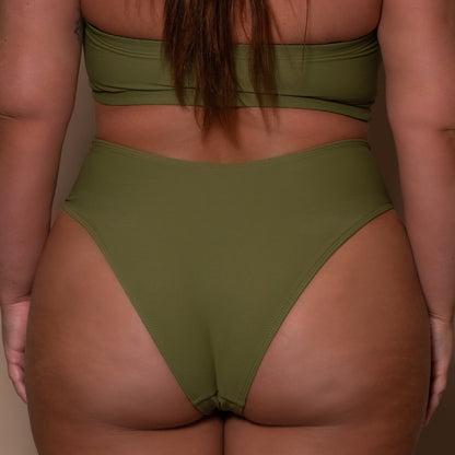 plussize woman wearing a khaki green bikini  against a beige background
