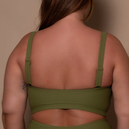 plussize woman wearing a khaki green bikini  against a beige background