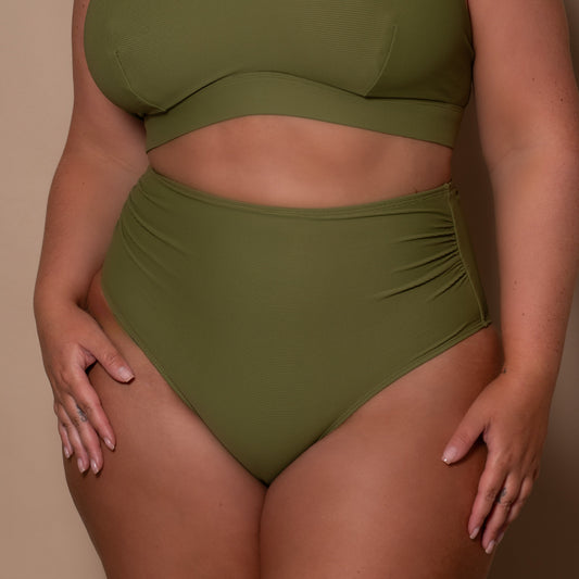 plussize woman wearing a khaki green bikini  against a beige background