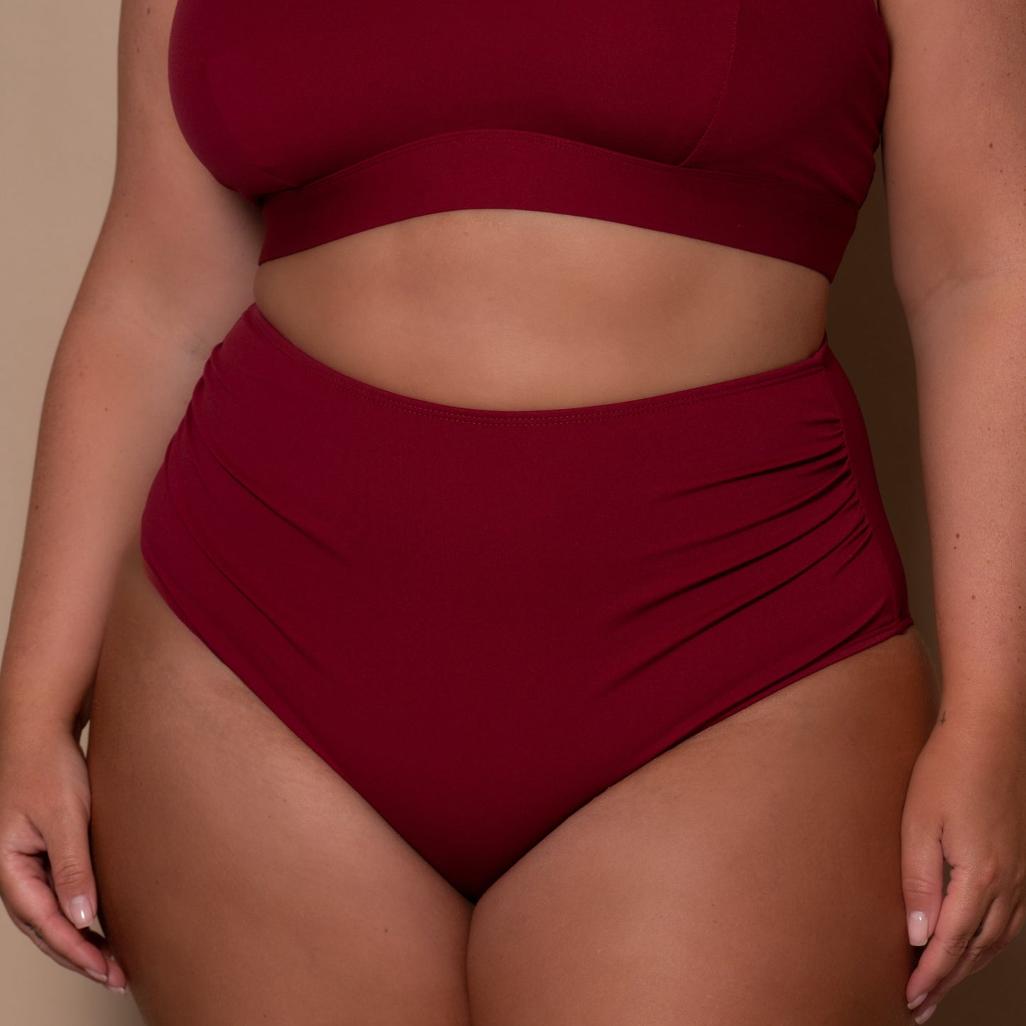 plussize woman wearing a pomegranate high waist red bikini  against a beige background