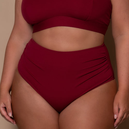 plussize woman wearing a pomegranate high waist red bikini  against a beige background