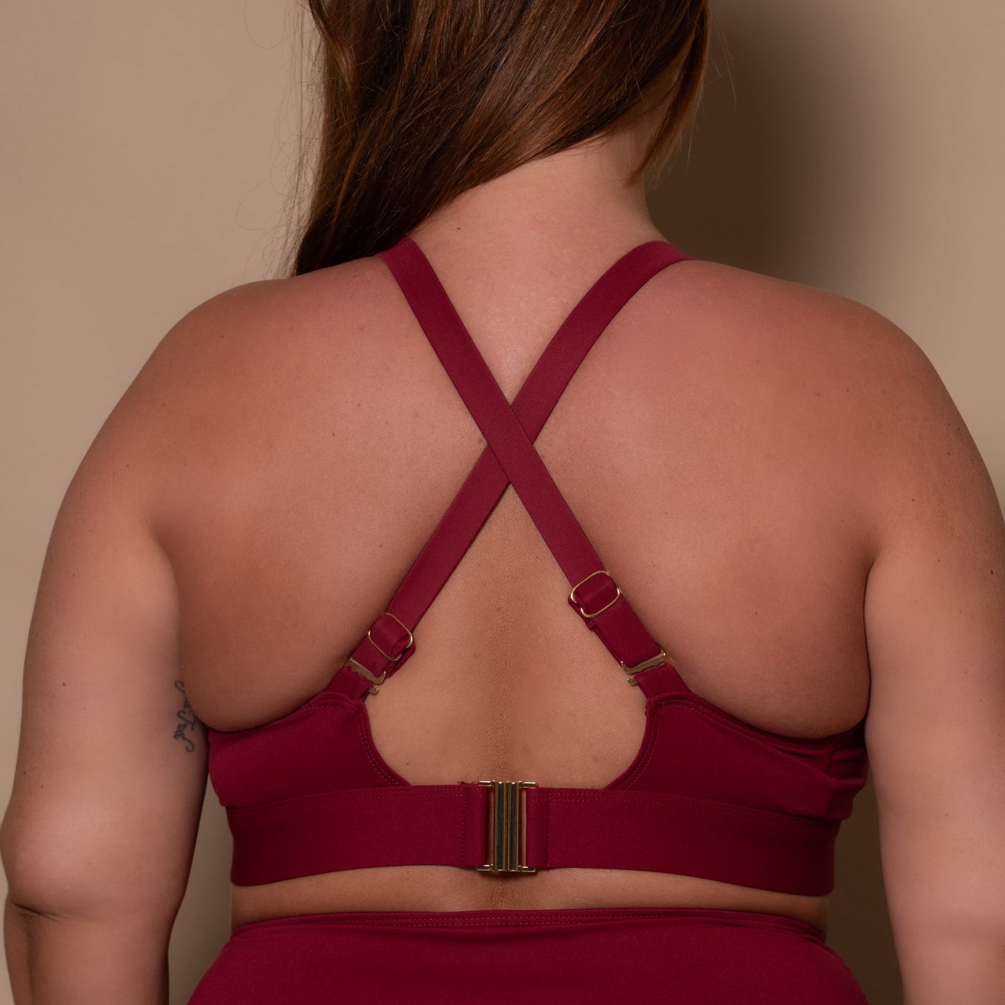 plussize woman wearing a pomegranate red bikini  against a beige background