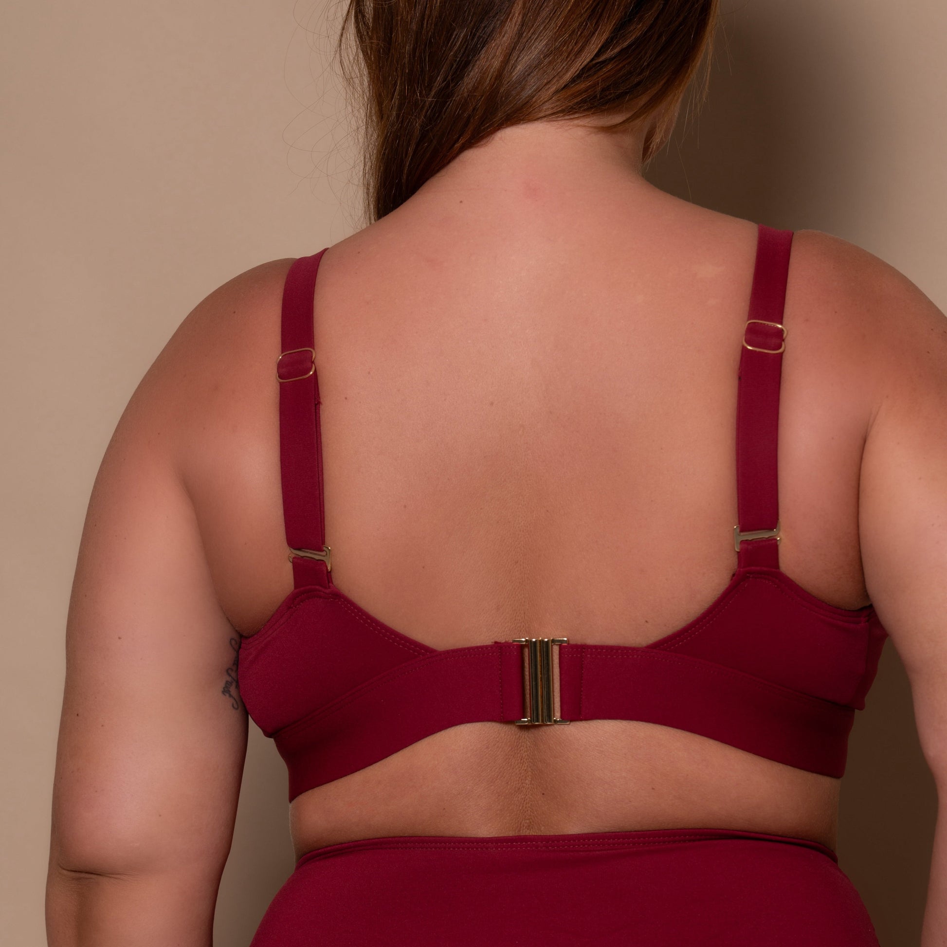 plussize woman wearing a pomegranate red bikini  against a beige background