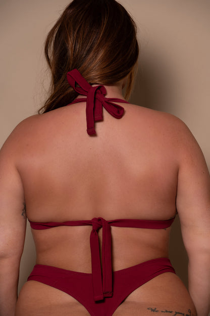 plussize woman wearing a pomegranate red bikini  against a beige background